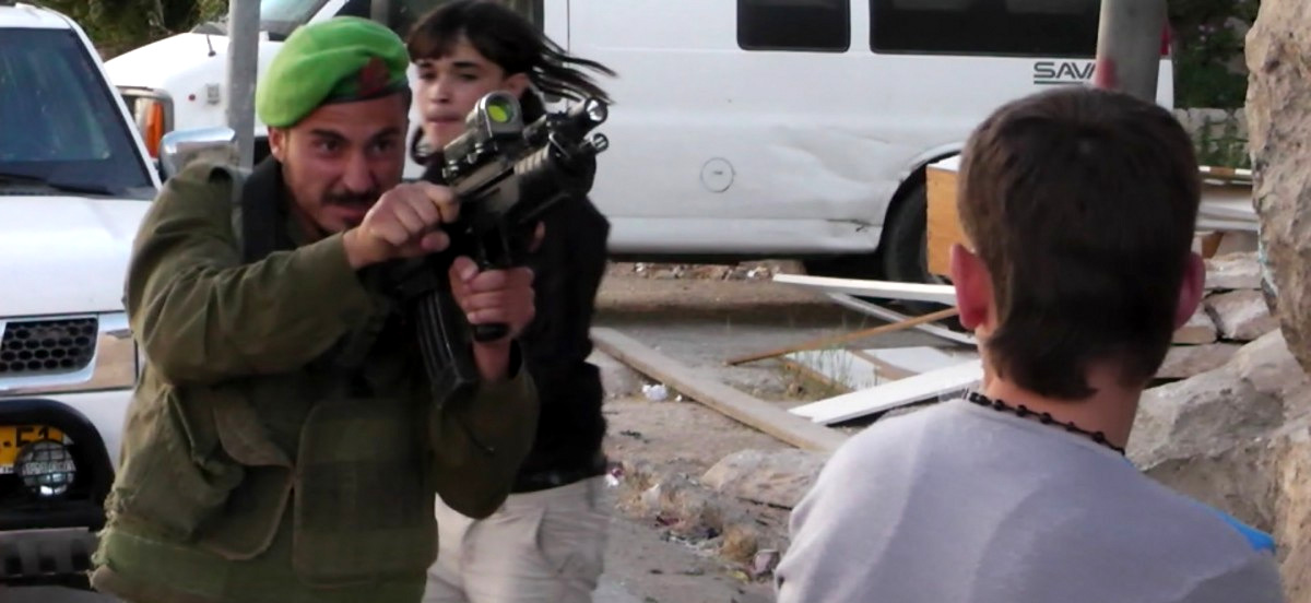 In this image taken from video obtained from Youth Against Settlements, a group of Palestinian activists, which has been authenticated based on its contents and other AP reporting, an Israeli soldier points his gun at a Palestinian teen in the West Bank city of Hebron. (AP Photo/Youth Against Settlements)