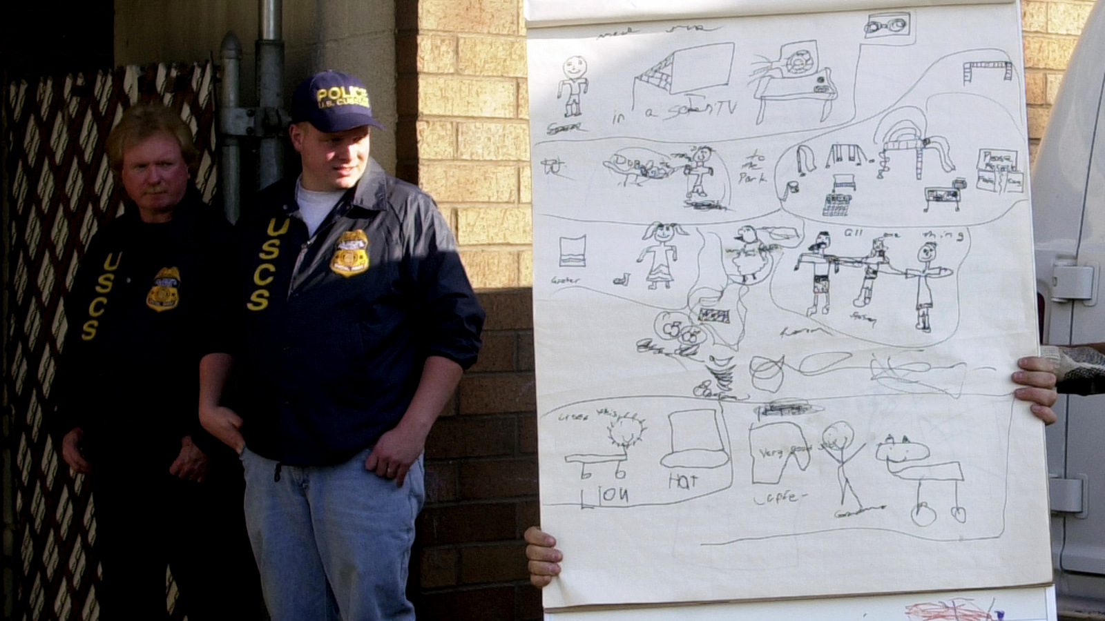 Un caballete con dibujos de niños es confiscado de las oficinas orientales de la Fundación Tierra Santa para el Socorro y el Desarrollo, mientras los agentes de Aduanas de los Estados Unidos hacen guardia en Paterson, N.J., el 4 de diciembre de 2001. (AP / Mike Derer)