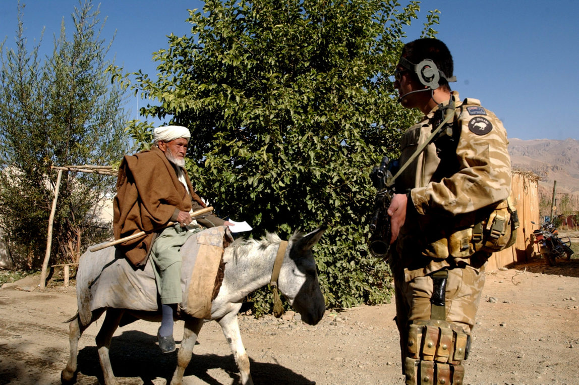 A New Zealand soldier stands guard as an elderly man rides a donkey north west of Kabul, Afghanistan, Oct. 5, 2006. (AP/Musadeq Sadeq)