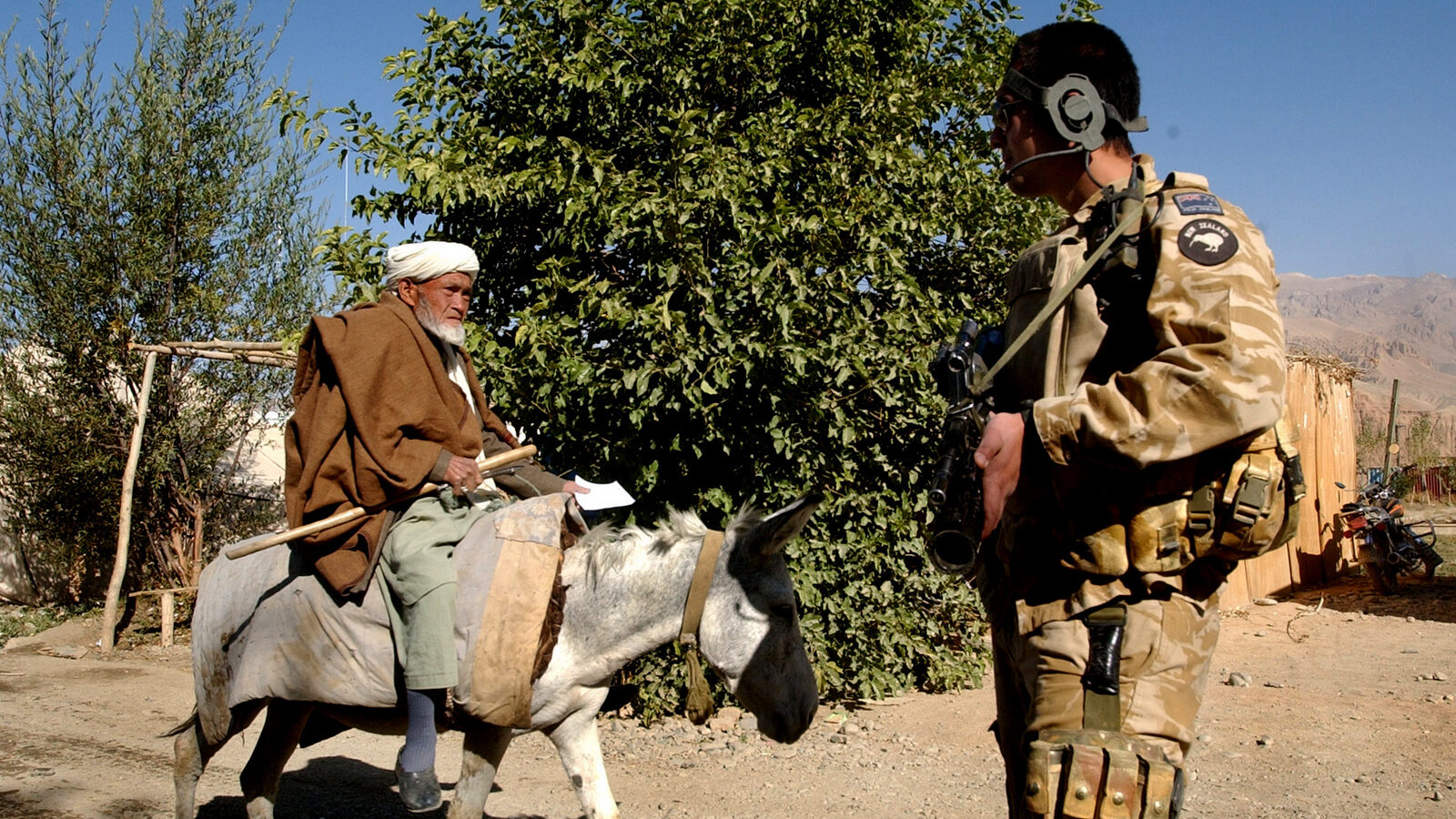 A New Zealand soldier stands guard as an elderly man rides a donkey north west of Kabul, Afghanistan, Oct. 5, 2006. (AP/Musadeq Sadeq)