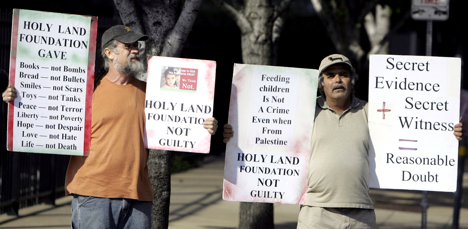 John Wolf, left, and Hadi Jawad hold signs supporting the Holy Land Foundation defendants while standing outside the federal courthouse in Dallas, Texas, Thursday, Oct. 18, 2007. (AP/LM Otero)
