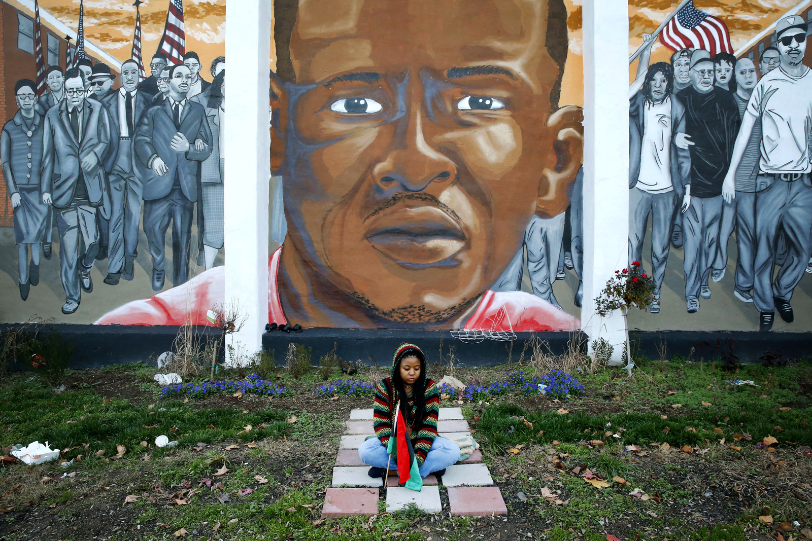 Jazmin Holloway sits below a mural depicting Freddie Gray at the intersection of his arrest, in Baltimore. Gray’s family agreed to a $6.4 million settlement with the city in September 2015. (AP/Patrick Semansky)
