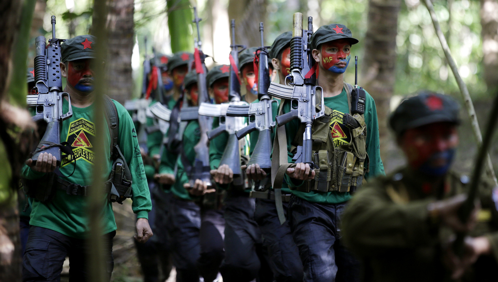 Members of the New People's Army march during the entry of colors as part of ceremonies before a news conference held at their guerrilla encampment tucked in the harsh wilderness of the Sierra Madre mountains southeast of Manila, Philippines. The group warns that a peace deal with President Rodrigo Duterte's government is unlikely if he won't end the Philippines' treaty alliance with the United States and resist control by other countries, Nov. 23, 2016. (AP/Aaron Favila)