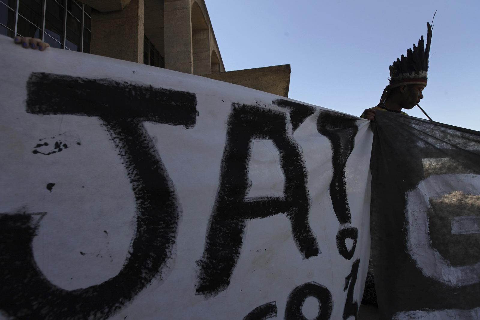 A Guarani Indian holds banner that reads in Portuguese "Now!", during a protest against President Michel Temer's plan to restrict land titles to indigenous communities, in Brasilia, Brazil, Aug. 30, 2017. (AP/Eraldo Peres)