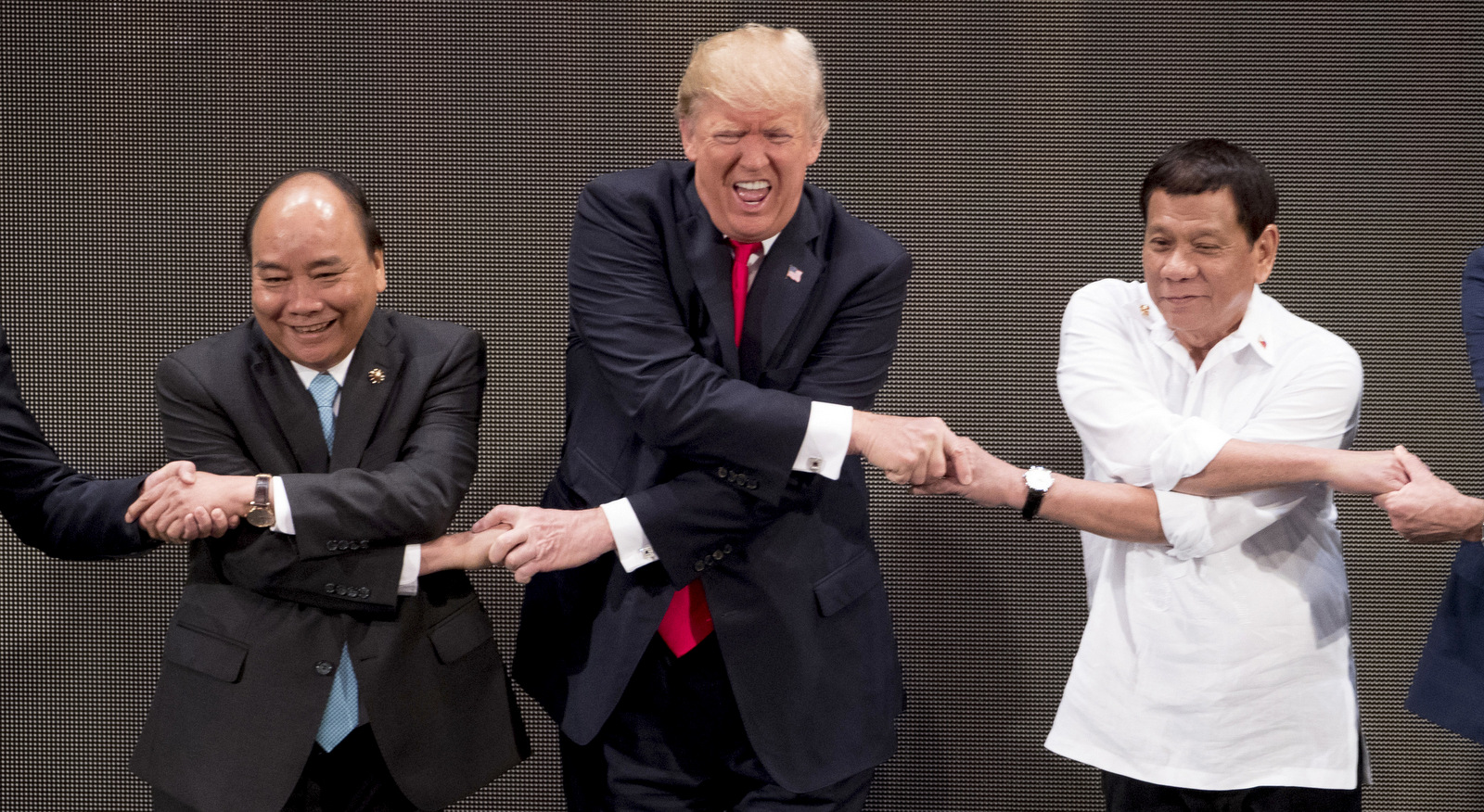 President Donald Trump, center does the "ASEAN-way handshake" with Vietnamese Prime Minister Nguyen Xuan Phuc, left, and Philippine President Rodrigo Duterte during the opening ceremony at the ASEAN Summit in the Philippines, Nov. 13, 2017. (AP/Andrew Harnik)