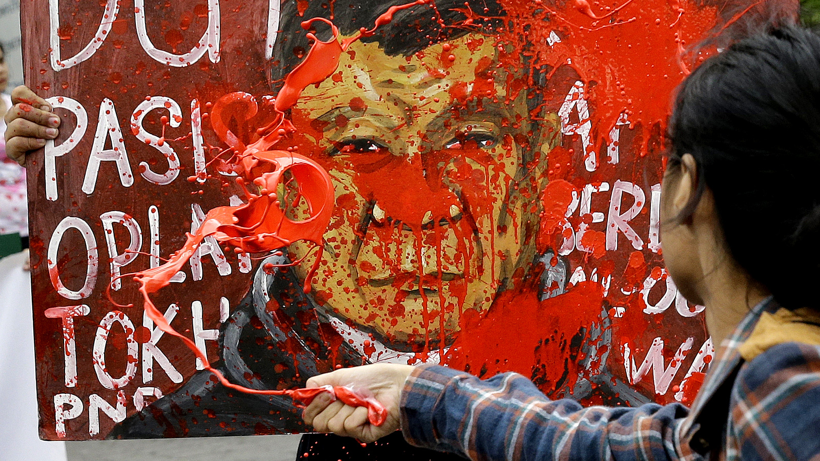A protester splashes red paint on a picture of Philippine President Rodrigo Duterte as they hold a rally near the Malacanang palace in Manila, Philippines, Dec. 7, 2017. The protesters are condemning the increase in the alleged killings of activists and intensified military operations against communist rebels after Duterte officially terminated peace talks with the insurgents. (AP/Aaron Favila)