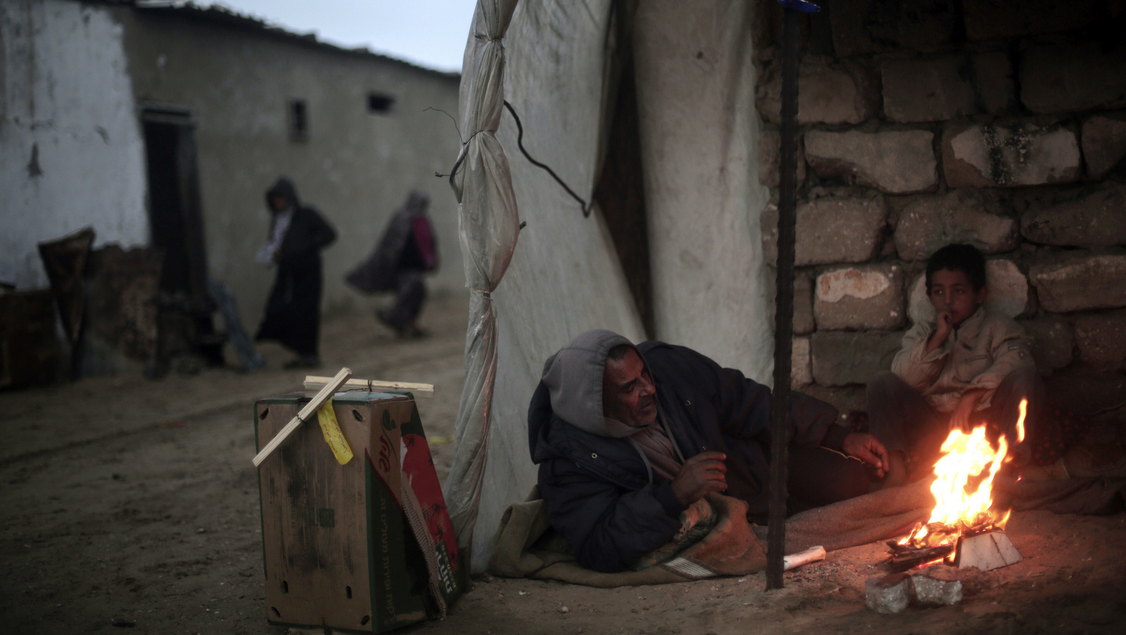 A Palestinian man and his son warm themselves by a fire during cold, rainy weather on the outskirts of the Khan Younis refugee camp in the southern Gaza Strip, Jan. 5, 2018. (AP/ Khalil Hamra)