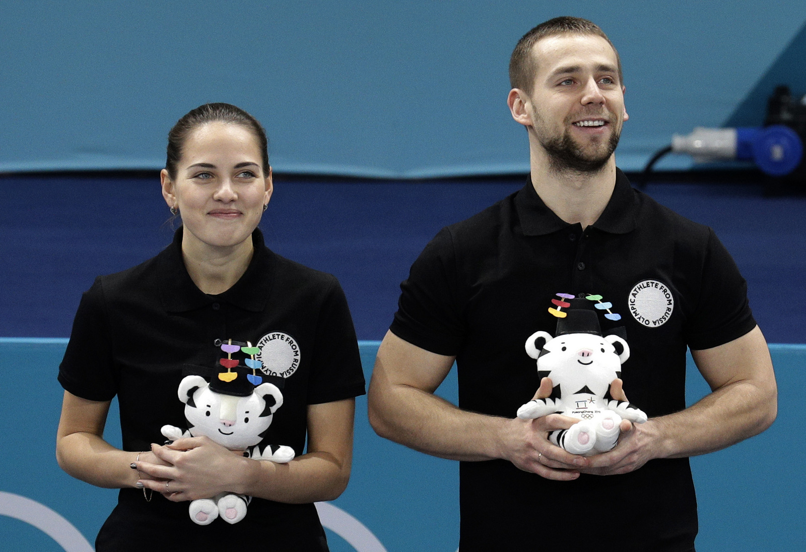 Russian athletes Anastasia Bryzgalova, left, and Alexander Krushelnitsky smile as they win bronze medal during the venue ceremony for the mixed doubles curling match at the 2018 Winter Olympics in Gangneung, South Korea, Feb. 13, 2018. (AP/Aaron Favila)