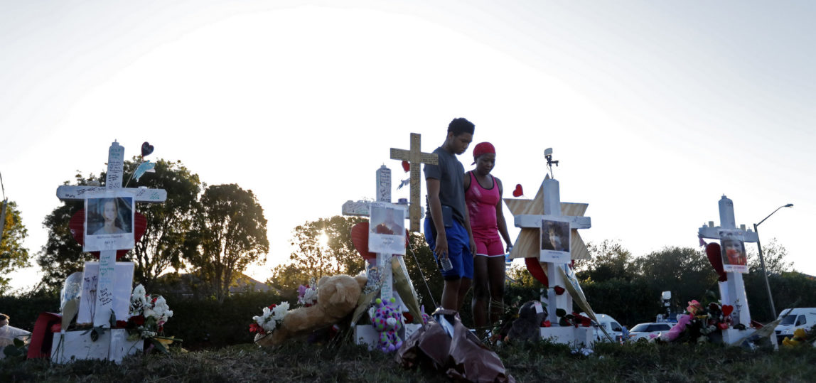 Denyse Christian, visits a makeshift memorial with her son Adin Christian, 16, a student at the school, outside the Marjory Stoneman Douglas High School, where 17 students and faculty were killed in a mass shooting, in Parkland, Fla., Feb. 19, 2018. (AP/Gerald Herbert)