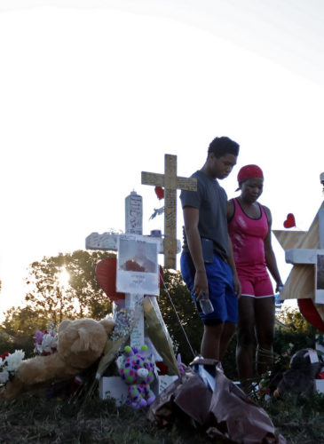 Denyse Christian, visits a makeshift memorial with her son Adin Christian, 16, a student at the school, outside the Marjory Stoneman Douglas High School, where 17 students and faculty were killed in a mass shooting, in Parkland, Fla., Feb. 19, 2018. (AP/Gerald Herbert)