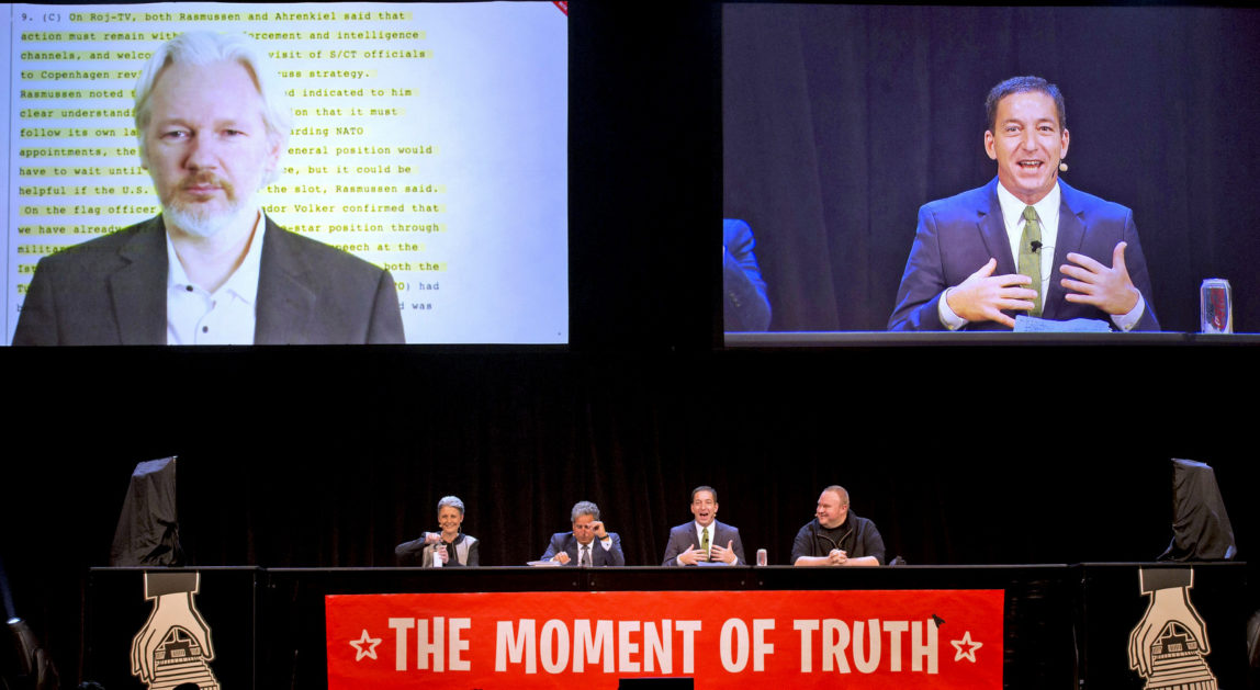 Wikileaks founder Julian Assange, top left, appears via video link with Glenn Greenwald, right, during a political forum at a town hall in Auckland, New Zealand, Sept. 15, 2014. (AP/New Zealand Herald, Brett Phibbs)