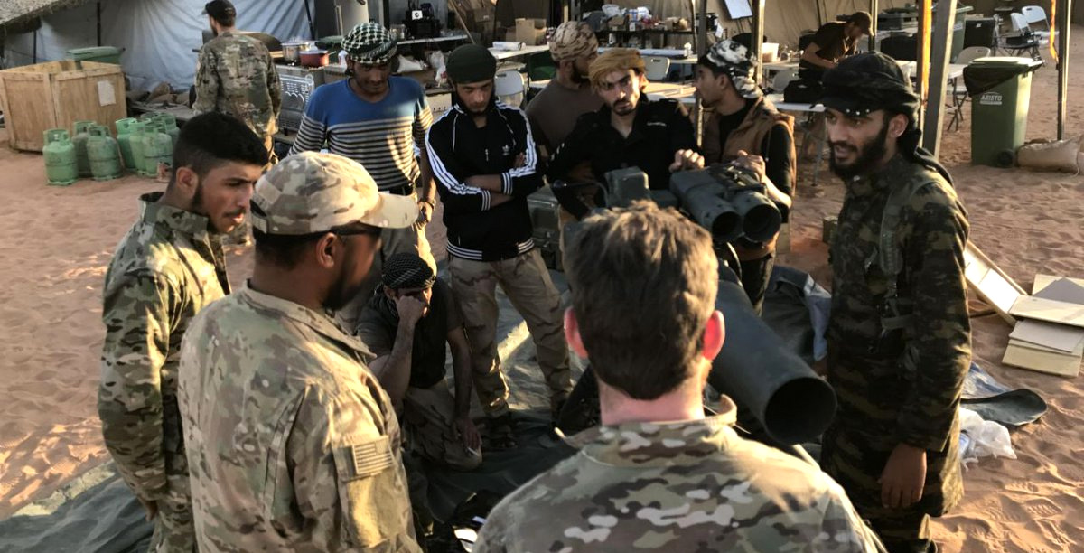 U.S.-backed anti-government Syrian rebels surround a piece of artillery while speaking to an American special forces member in Southern Syria near Tanf. (Hammurabi’s Justice News/AP)