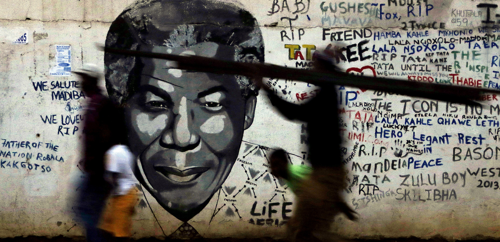 People walk past a mural of former South African President Nelson Mandela in Katlehong, south of Johannesburg, South Africa, May 11, 2015. (AP/Themba Hadebe)