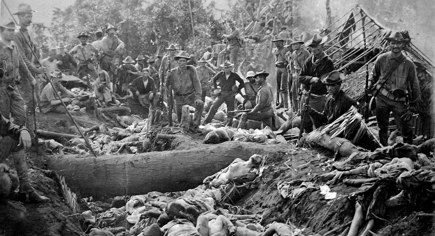 US soldiers pose with the bodies of fallen Moros men, women and children, who resisted US colonial rule in the Philippines. The bodies were piled five deep in the trenches of the crater of an extinct volcano, Bud Dajo, where they had been mowed down by artillery, machine gun and rifle fire from American forces. (Public Domain)