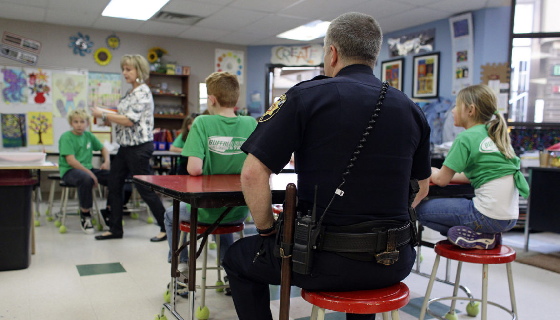 A Douglas County Sheriff sits in on part of an art class at Buffalo Ridge Elementary School, part of a new cooperative effort between law enforcement and schools for more routine police presence at local elementary schools, in Castle Pines, Colo. (AP/Brennan Linsley)