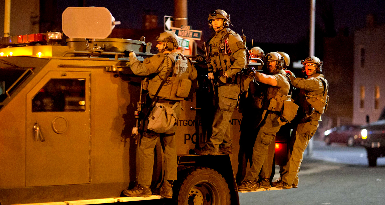 Police ride on an armored vehicle through Baltimore on an armored vehicle following protests which occurred after the funeral of Freddie Gray, who was killed by police. A 10 p.m. curfew was in effect, April 28, 2015 (AP/David Goldman)