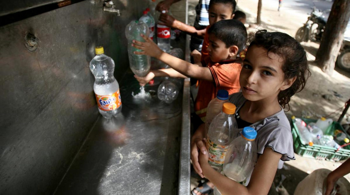 Palestinian children fill their bottles with water from a UNICEF tap in Rafah in the southern Gaza Strip. (Photo: UNICEF)