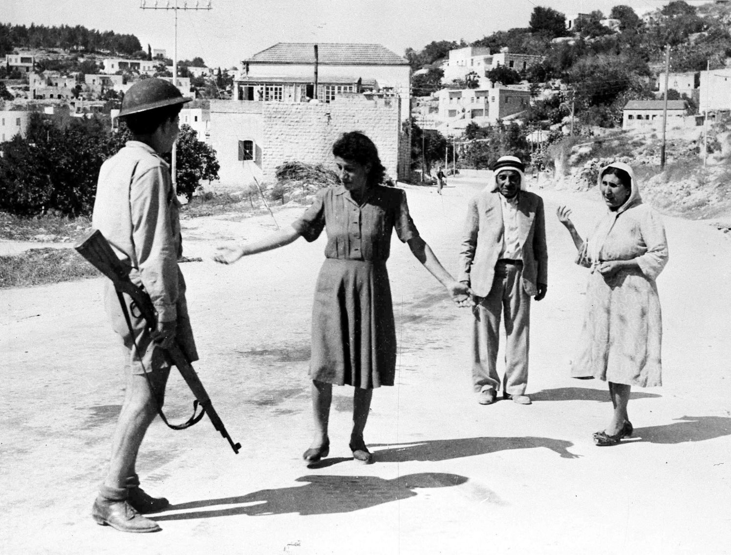 An Israeli soldier, armed with a rifle, stop some arabs in a street in Nazareth, Palestine, July 17, 1948, as they are travelling after the allotted curfew time. Israeli forces had occupied the town earlier that day. (AP Photo)