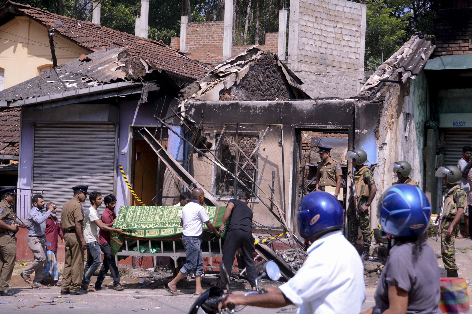 Sri Lankan police personnel stand near a vandalized building as they prepare to remove the body of a man who was killed in Digana, a suburb of Kandy, Sri Lanka, March 6, 2018. Buddhist mobs swept through the town burning at least 11 Muslim-owned shops and homes. (AP/Pradeep Pathiran)