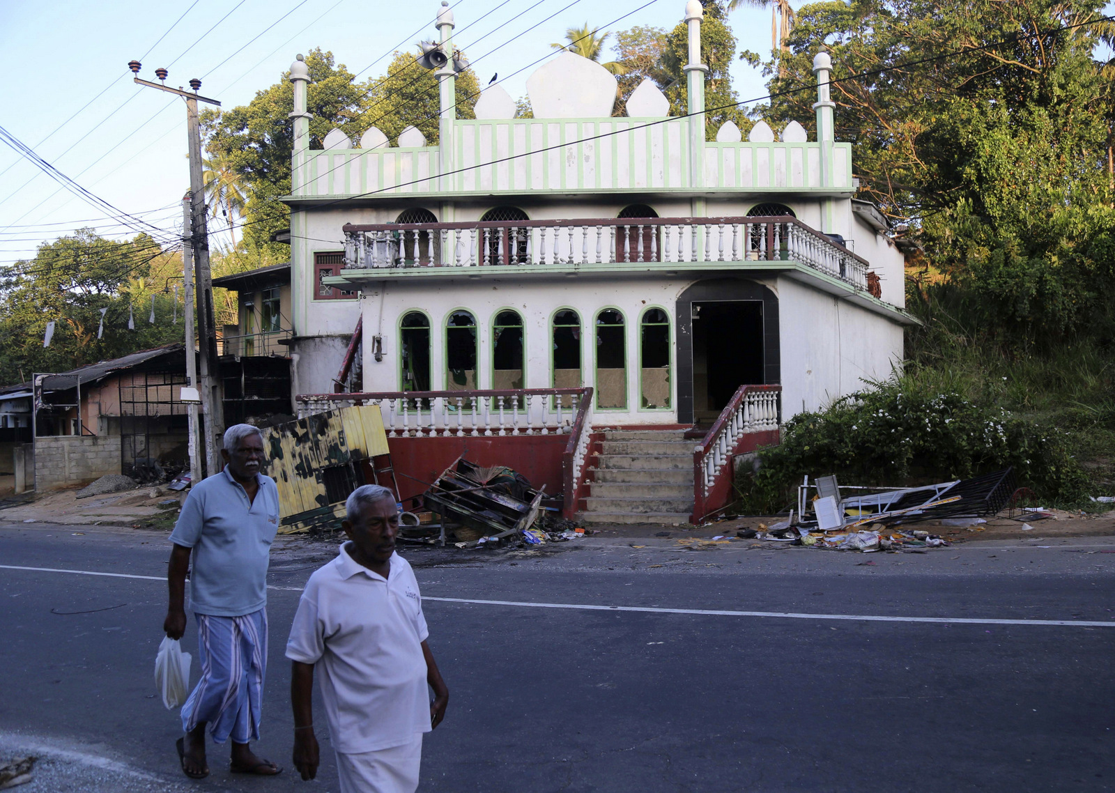 Sri Lankans walk past a vandalized Mosque in Diana, in central Sri Lanka, March 7, 2018. Sri Lanka's president declared a state of emergency after anti-Muslim attacks in several central hill towns. (AP/Rukmal Gamage)