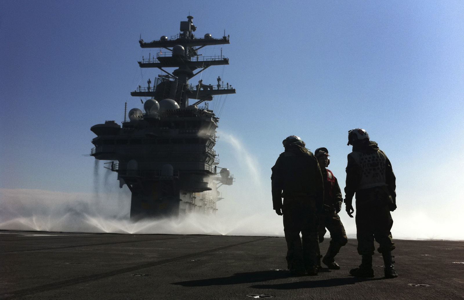 U.S. Navy deck crew stand near the island on the deck which is sprayed for radioactive decontamination aboard USS Ronald Reagan (CVN76) in the Pacific Ocean off the Japanese coast, March 23, 2011. (AP/Eugene Hoshiko)