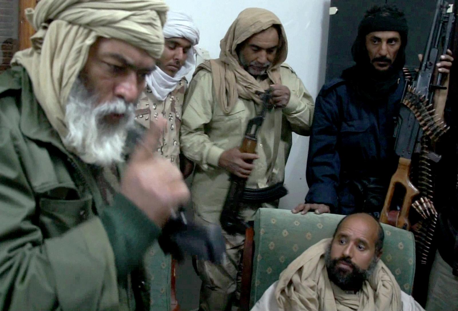 In this image taken from video made available Tuesday, Nov. 22, 2011, Moammar Gadhafi's son Saif al-Islam Gaddafi, below right, is surrounded by Libyan captors shortly after his capture on Nov. 19, 2011, at a safe house in the town of Zintan, Libya. The video shows Seif al-Islam arguing with his captors and admonishing them, saying that Libya's regions that were united in revolution will turn against each other in the near future and rip the country apart. (AP/APTN)
