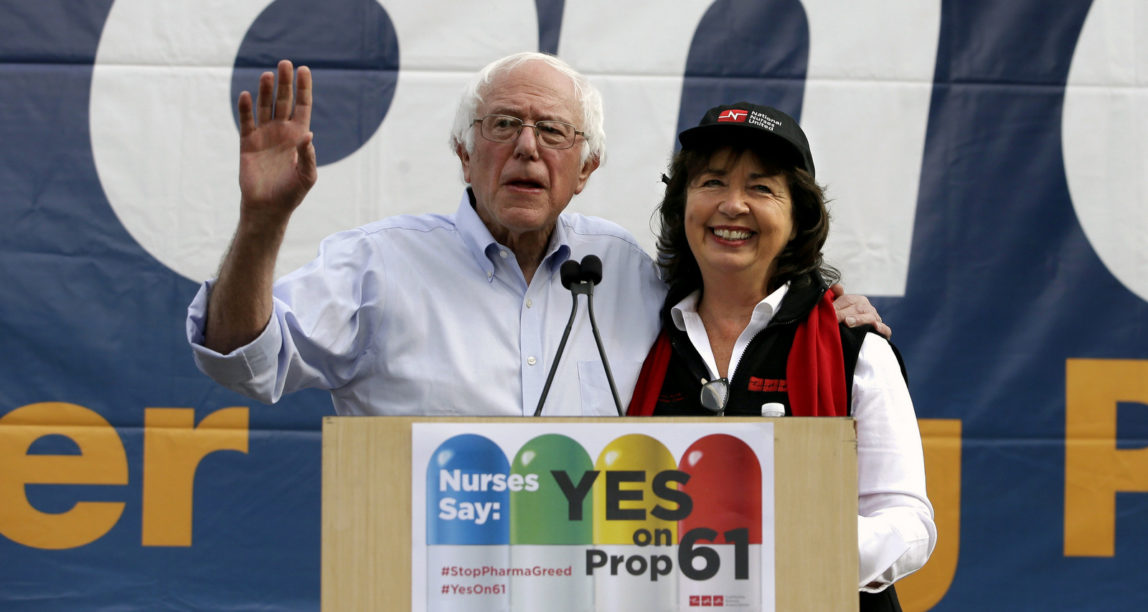 Former presidential candidate Sen. Bernie Sanders, of Vermont,, left, flanked by RoseAnn DeMoro, executive director of National Nurses United, speaks in support of Proposition 61 in Sacramento, Calif., Nov. 7, 2016. (AP/Rich Pedroncelli)