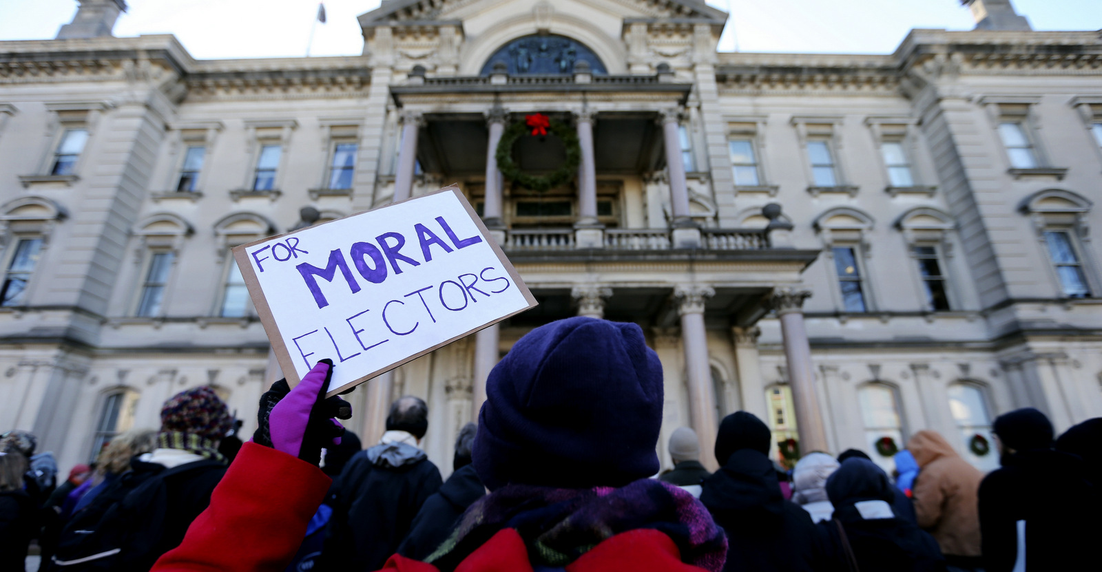 A protester holds up a sign as a group demonstrates in freezing temperatures at the Statehouse, ahead of New Jersey's Electoral College, Monday, Dec. 19, 2016, in Trenton, N.J. (AP/Mel Evans)
