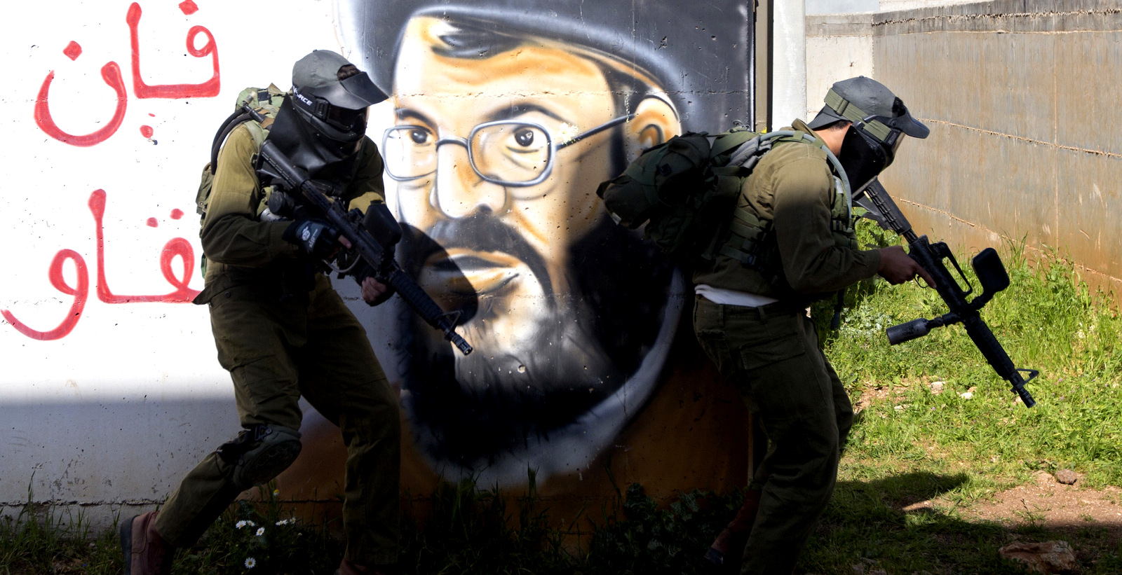 Israeli soldiers train with paintball guns during a drill at an Army base near Elyakim, Israel. Between myriad concrete buildings with Arabic graffiti that are designed to simulate a typical Lebanese village, dozens of Israeli officers are gearing up for their next battle with Hezbollah. The Arabic is random letters, and the graffiti depicts Hezbollah's leader Hassan Nasrallah, March 29, 2017.(AP/Sebastian Scheiner)