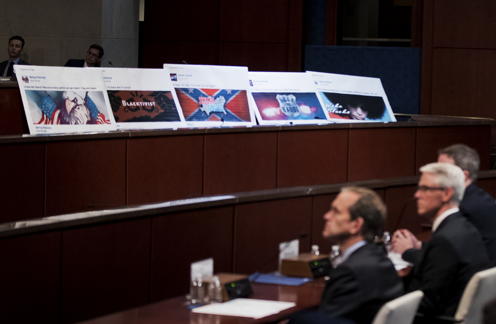 Facebook ads linked to a purported Russian effort to disrupt the American political process are displayed as, from left, Google's Senior Vice President and General Counsel Kent Walker, Facebook's General Counsel Colin Stretch, and Twitter's Acting General Counsel Sean Edgett, testify during a House Intelligence Committee hearing on Capitol Hill in Washington, Nov. 1, 2017. (AP/Manuel Balce Ceneta)