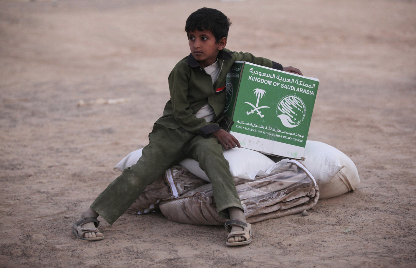 A young Yemeni boy living in a camp for people displaced by his country's war holds a box of aid from Saudi Arabia in Marib, Yemen, Feb. 1, 2018. (AP/Jon Gambrell)