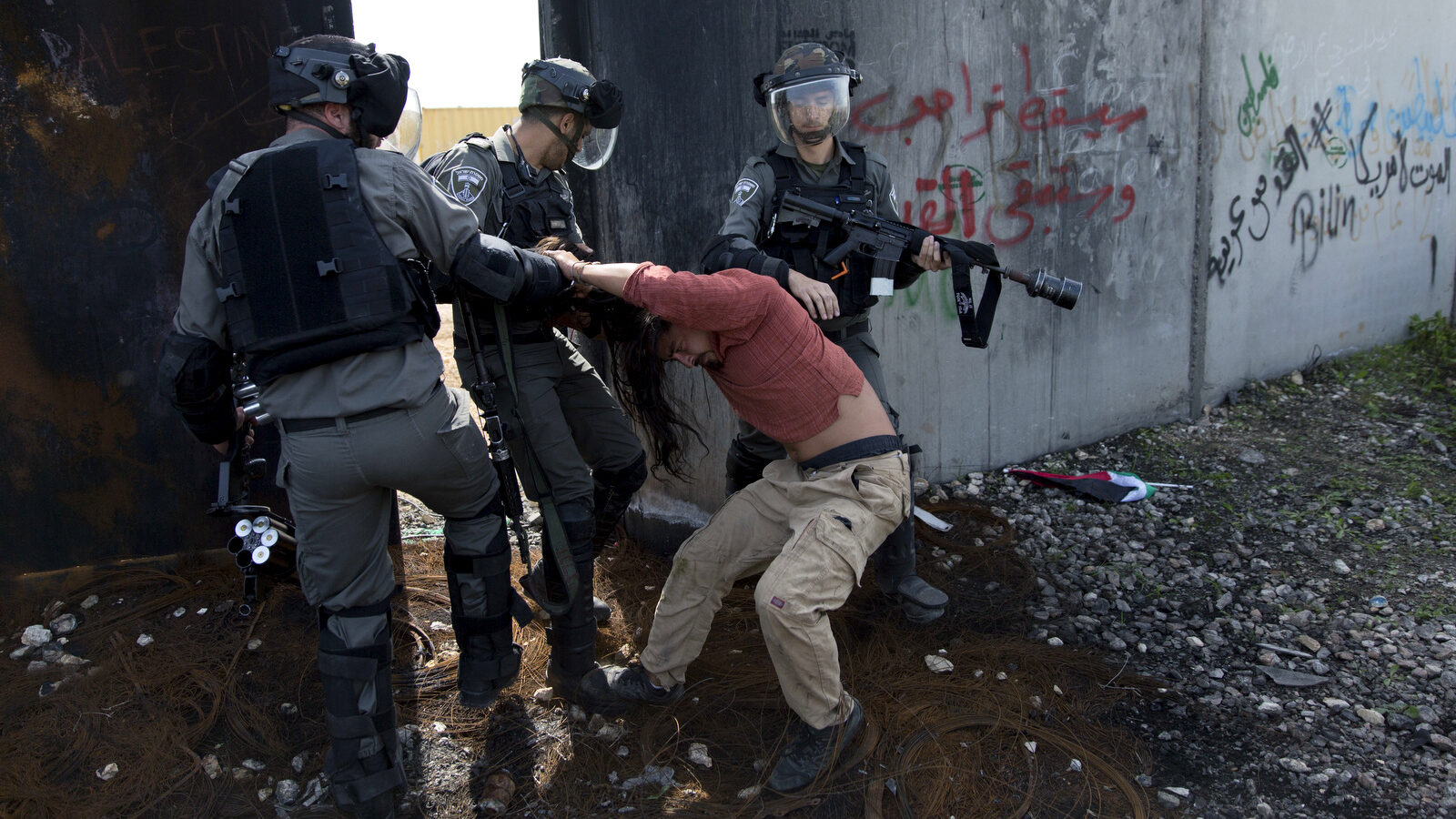 Israeli border police drag an activist by the next to Israel's apartheid wall during a protest in the occupied West Bank village of Bil'in, west of Ramallah, March 2, 2018. Palestinian protesters and foreign activists marched to commemorate the 13th anniversary of the ongoing weekly protests against the Israeli apartheid wall and Jewish-only settlements in Bil'in. (AP/Nasser Nasser)Israeli border police drag an activist by the next to Israel's apartheid wall during a protest in the occupied West Bank village of Bil'in, west of Ramallah, March 2, 2018. Palestinian protesters and foreign activists marched to commemorate the 13th anniversary of the ongoing weekly protests against the Israeli apartheid wall and Jewish-only settlements in Bil'in. (AP/Nasser Nasser)