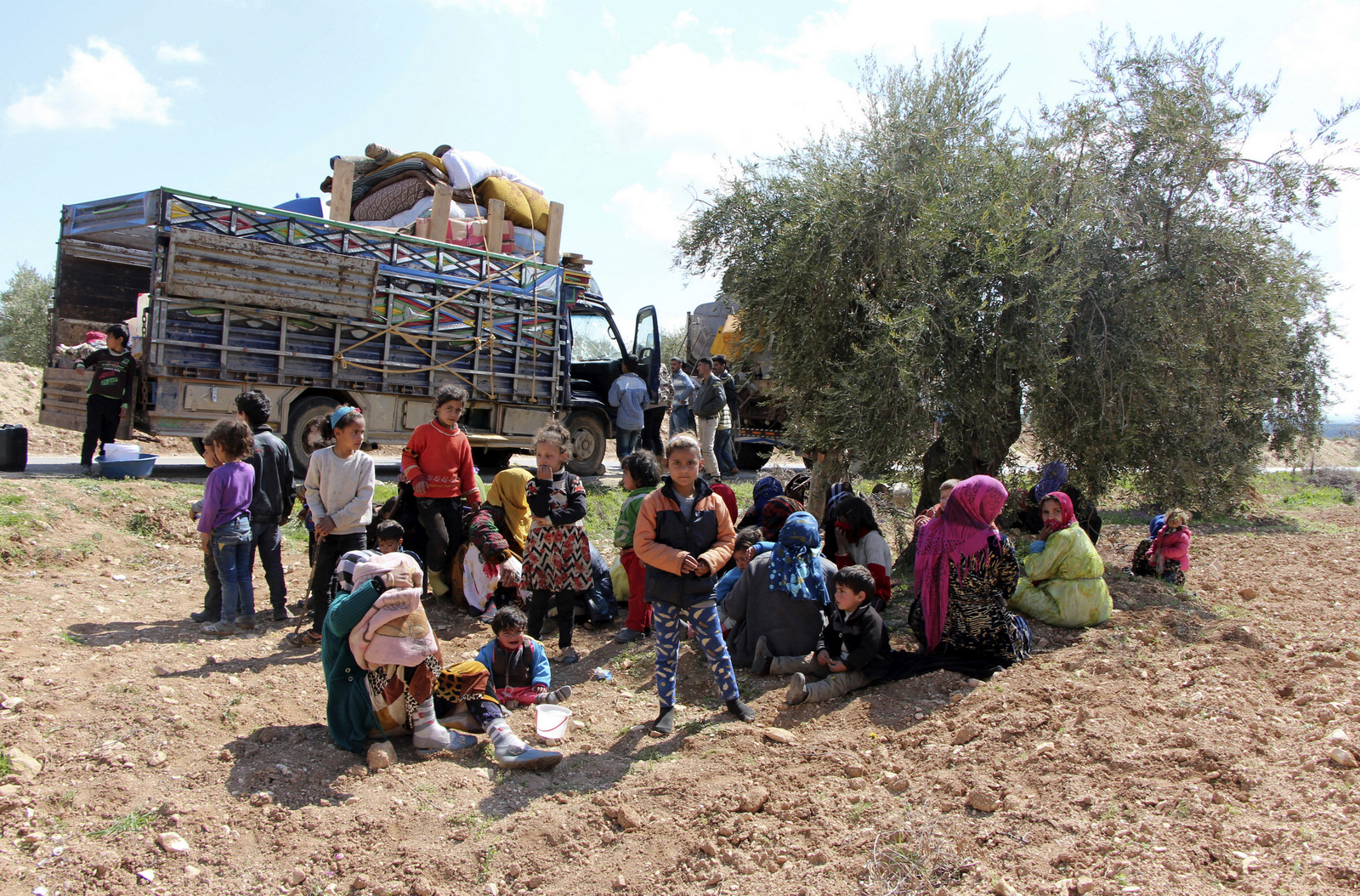 Syrians fleeing fighting between Turkish troops and Syrian Kurdish militia rest in a field between Afrin and Azaz, northwestern Syria, March 14, 2018. (DHA-Depo via AP)