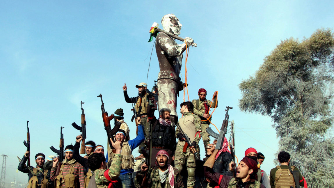 Turkey-backed Free Syrian Army soldiers celebrate around a statue of Kawa, a mythology figure in Kurdish culture as they prepare to destroy it in city center of Afrin, northwestern Syria, March 18, 2018. (Hasan Kırmızitaş/DHA-Depo Photos via AP)