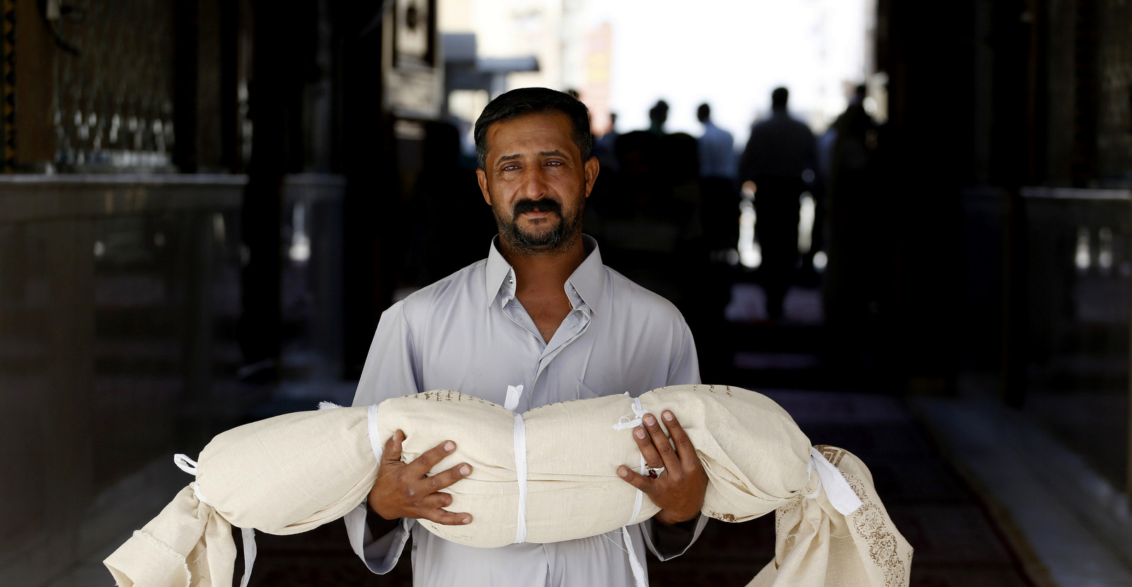 Qasim Ahmed Tahan carries the dead body of his 5-year-old son, Walid, who was killed in a bombing before burial in Najaf, Iraq, Sept. 14, 2013. (AP/Jaber al-Helo)