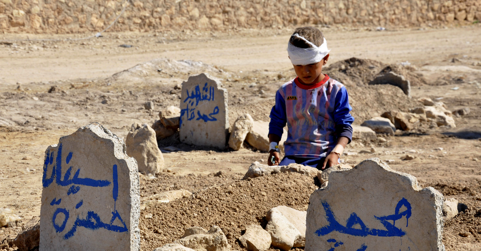 Ali Hamza, 8, sits at the graves of his brother, Mohammed, and sister Asinat, who were killed at their school when a suicide car bomb attack near Qabak elementary school in the Shiite Turkomen village of Qabak, Iraq, Oct. 7, 2013. (AP Photo)