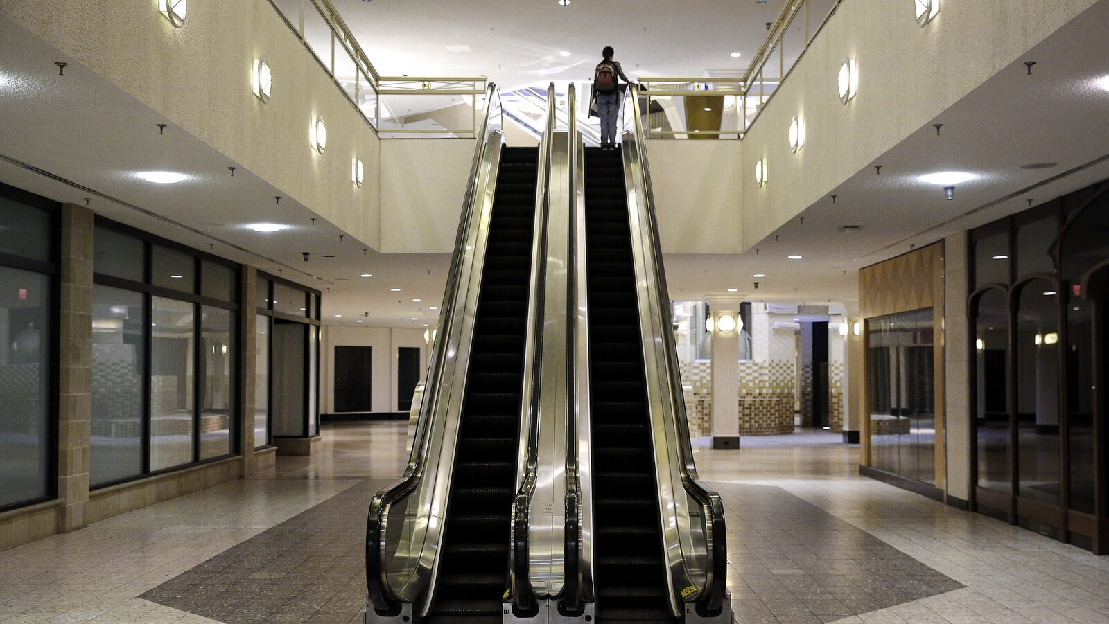 A woman rides an escalator past closed storefronts inside the largely empty White Flint Mall in Bethesda, Md. Opened in 1977, just two tenants remain. (AP/Patrick Semansky)