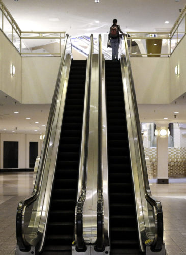 A woman rides an escalator past closed storefronts inside the largely empty White Flint Mall in Bethesda, Md. Opened in 1977, just two tenants remain. (AP/Patrick Semansky)