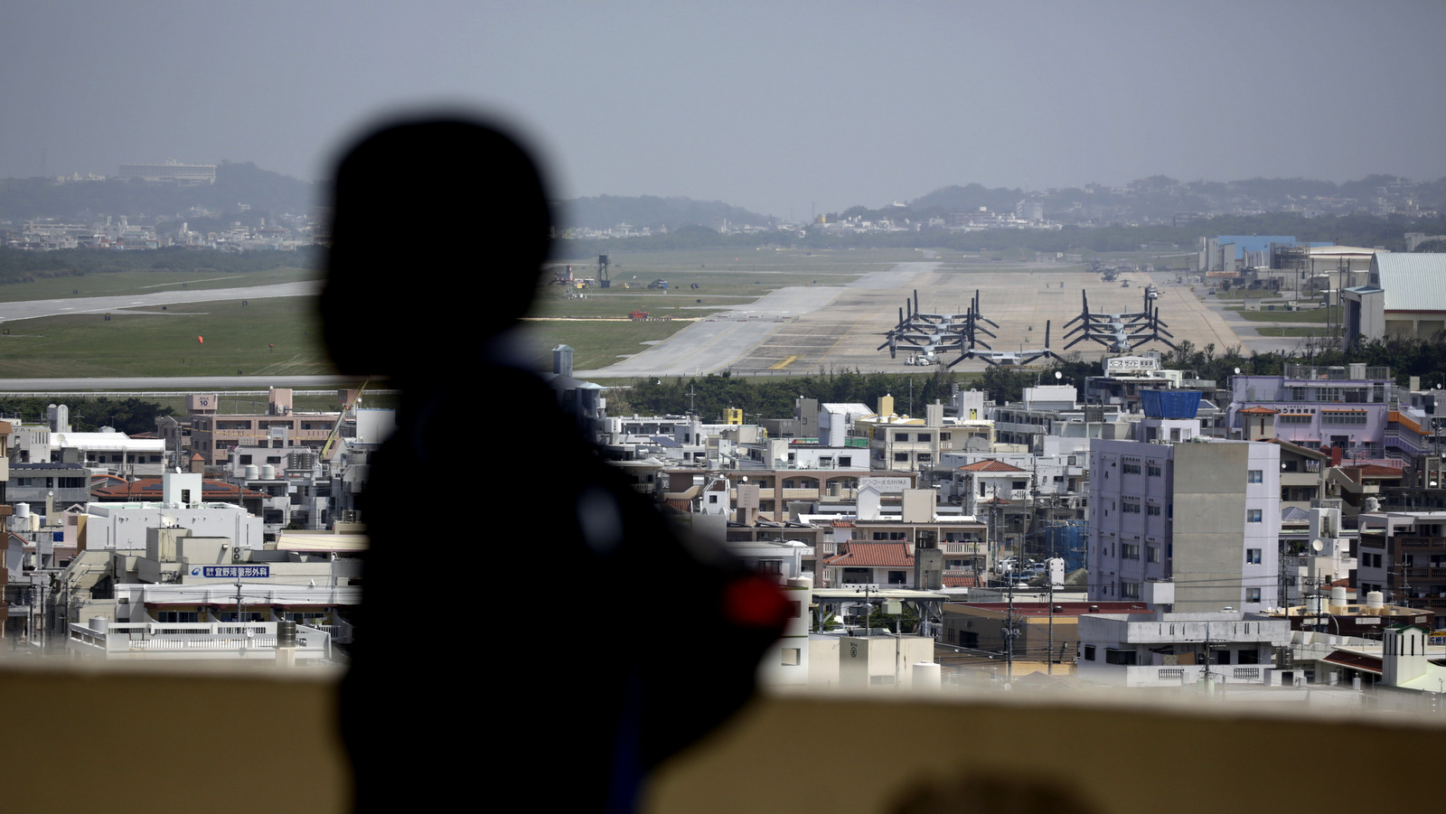 A child looks at the U.S. Marine Corps Futenma Air Station and the surrounding area from an observation deck at a park in Ginowan, Okinawa Prefecture on southern Japan, March 23, 2015 (AP/Eugene Hoshiko)