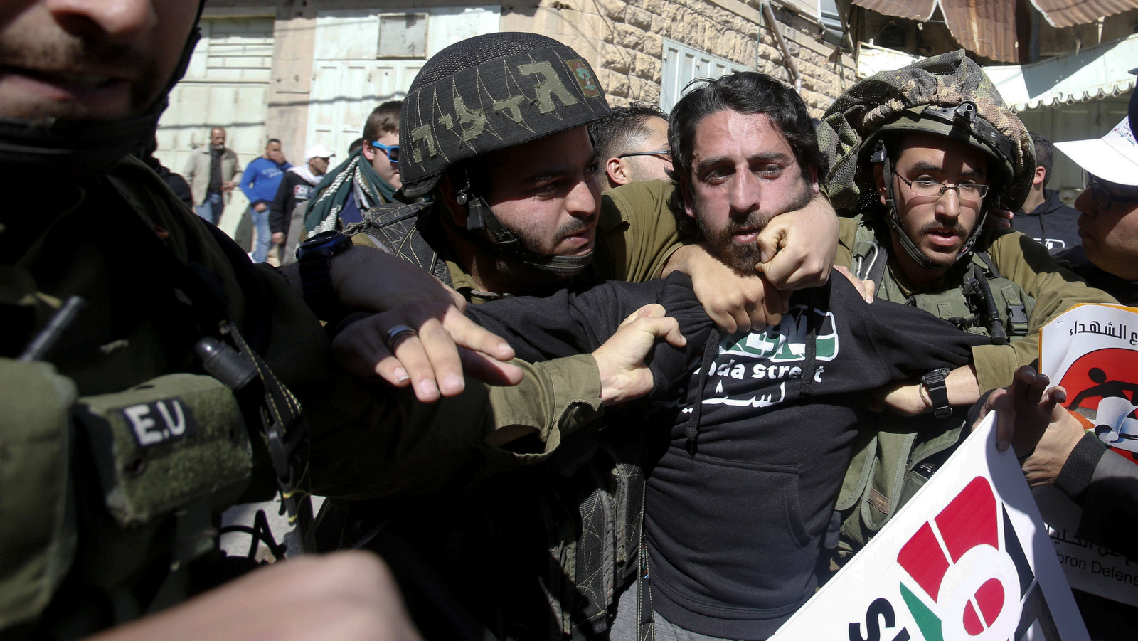 以色列士兵在2015年2月27日逮捕了要求在西岸城市希布伦重新开放舒哈达街的青年反对定居者抗议者。1994年，以色列杀害29名巴勒斯坦人，并在一次祈祷中造成100多人受伤，以色列于1994年关闭了舒哈达街。清真寺。 （美联社/纳赛尔·史基）