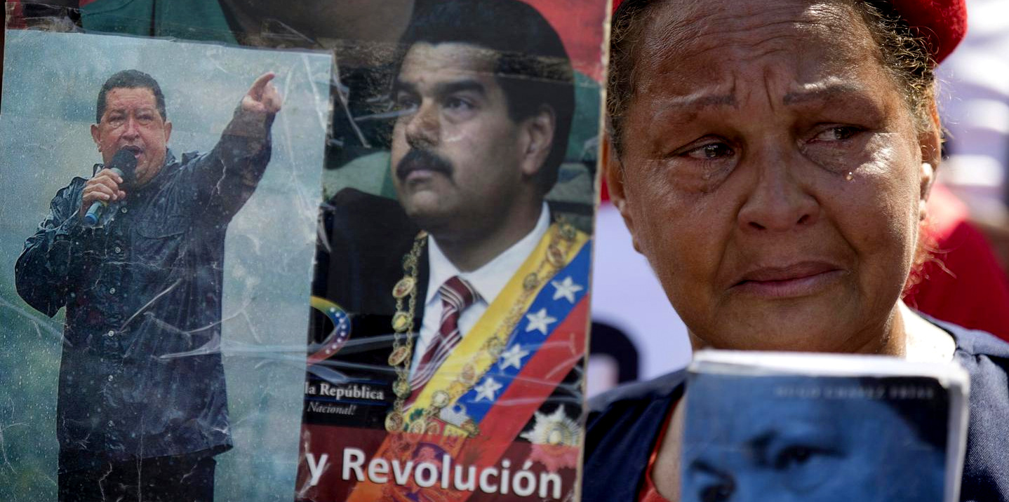 A supporter of Hugo Chavez cries as she holds pictures of Chavez and President Nicolas Maduro during a rally marking the fifth anniversary of Chavez's death, in Caracas, Venezuela, March 15, 2018. (AP/Fernando Llano)