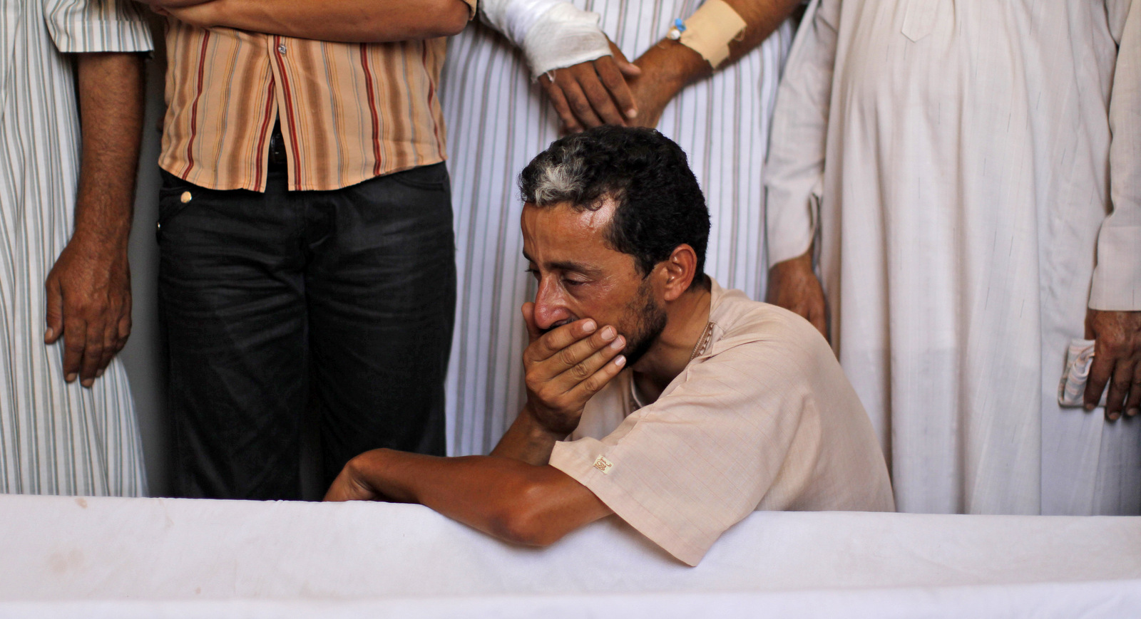 A relative of two children and their mother, who died after a NATO bomb fell on their home, grieves during their funeral in Zlitan, Libya, Aug. 4, 2011. (AP/Dario Lopez-Mills)