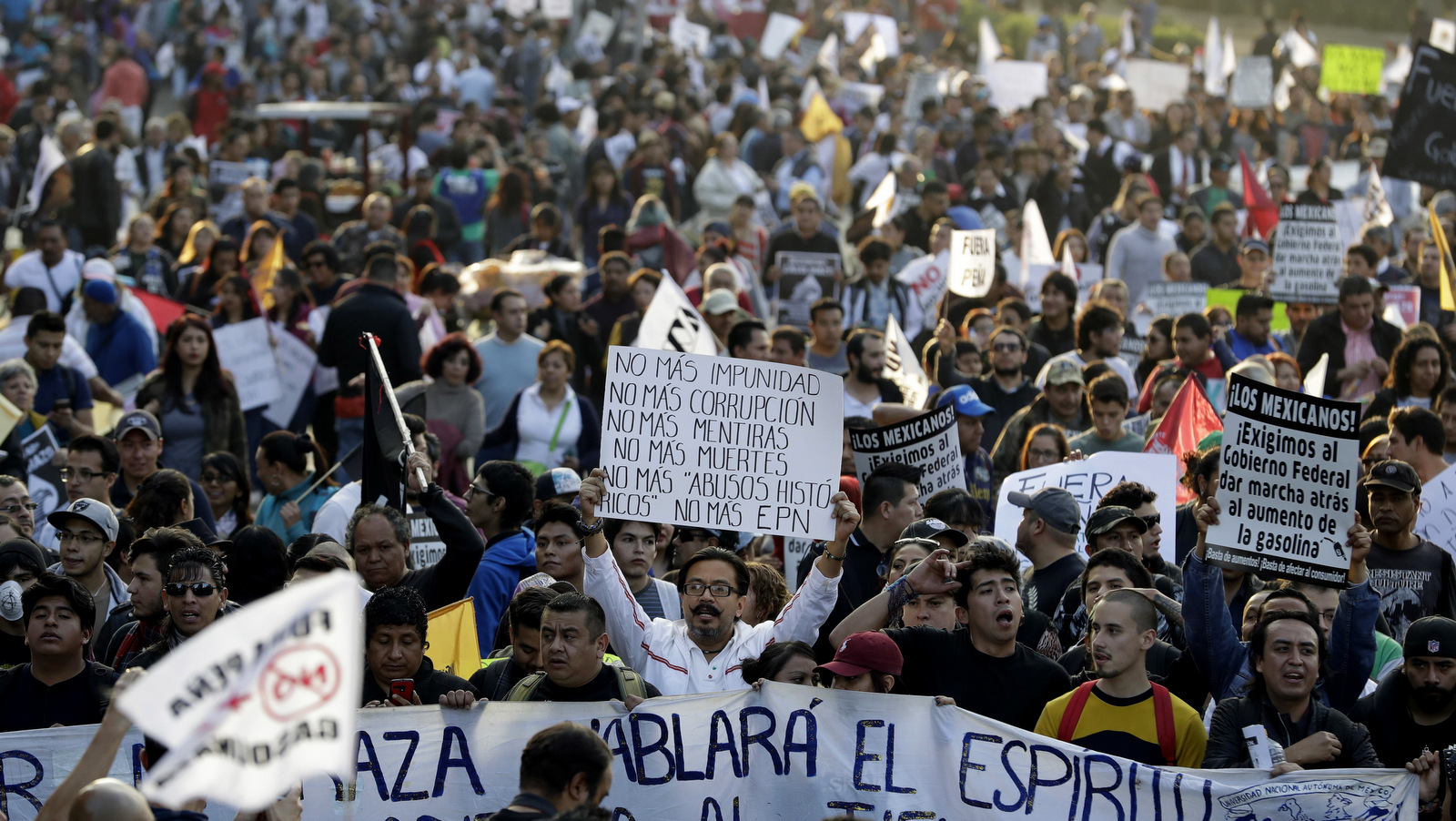 A man carries a sign reading in Spanish "No more impunity, no more corruption, no more lies, no more death, no more 'historic abuses,' no more EPN," as thousands marched in anger against the government of Enrique Pena Nieto following a 20 percent rise in gas prices, in Mexico City, Jan. 9, 2017. (AP/Rebecca Blackwell)