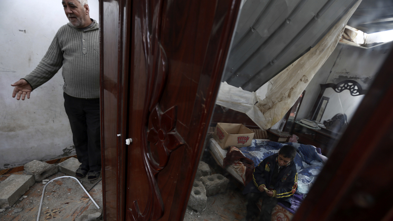 Palestinians check their damaged homes following early morning Israeli airstrikes in town of Khan Younis, southern Gaza Strip, Wednesday, Dec. 13, 2017. The Israeli military says it has carried out airstrikes in Gaza is response to rocket fire toward southern Israel. The military says it struck a Hamas military compound in southern Gaza early on Wednesday. No casualties were reported. (AP Photo/Khalil Hamra)