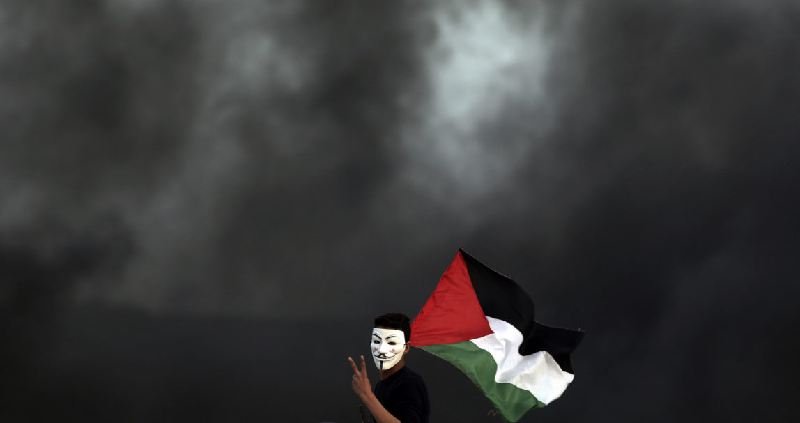A protester holding a Palestinian flag flashes the victory sign for a photographer during a protest at the Gaza Strip border with Israel, in eastern Gaza City, Wednesday, April 4, 2018. A leading Israel human rights group urged Israeli forces in a rare step Wednesday to disobey open-fire orders unless Gaza protesters pose an imminent threat to soldiers' lives. (AP Photo/Khalil Hamra)
