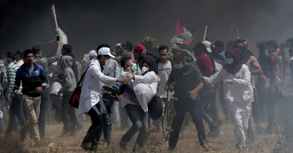 Palestinian medics evacuate a wounded colleague during clashes with Israeli troops along Gaza's border with Israel, east of Khan Younis, Friday, April 6, 2018. Palestinians torched piles of tires near Gaza's border with Israel on Friday, sending huge plumes of black smoke into the air and drawing Israeli fire that killed one man in the second large protest in the volatile area in a week. (AP Photo/Adel Hana)