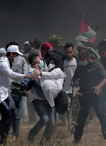 Palestinian medics evacuate a wounded colleague during clashes with Israeli troops along Gaza's border with Israel, east of Khan Younis, Friday, April 6, 2018. Palestinians torched piles of tires near Gaza's border with Israel on Friday, sending huge plumes of black smoke into the air and drawing Israeli fire that killed one man in the second large protest in the volatile area in a week. (AP Photo/Adel Hana)