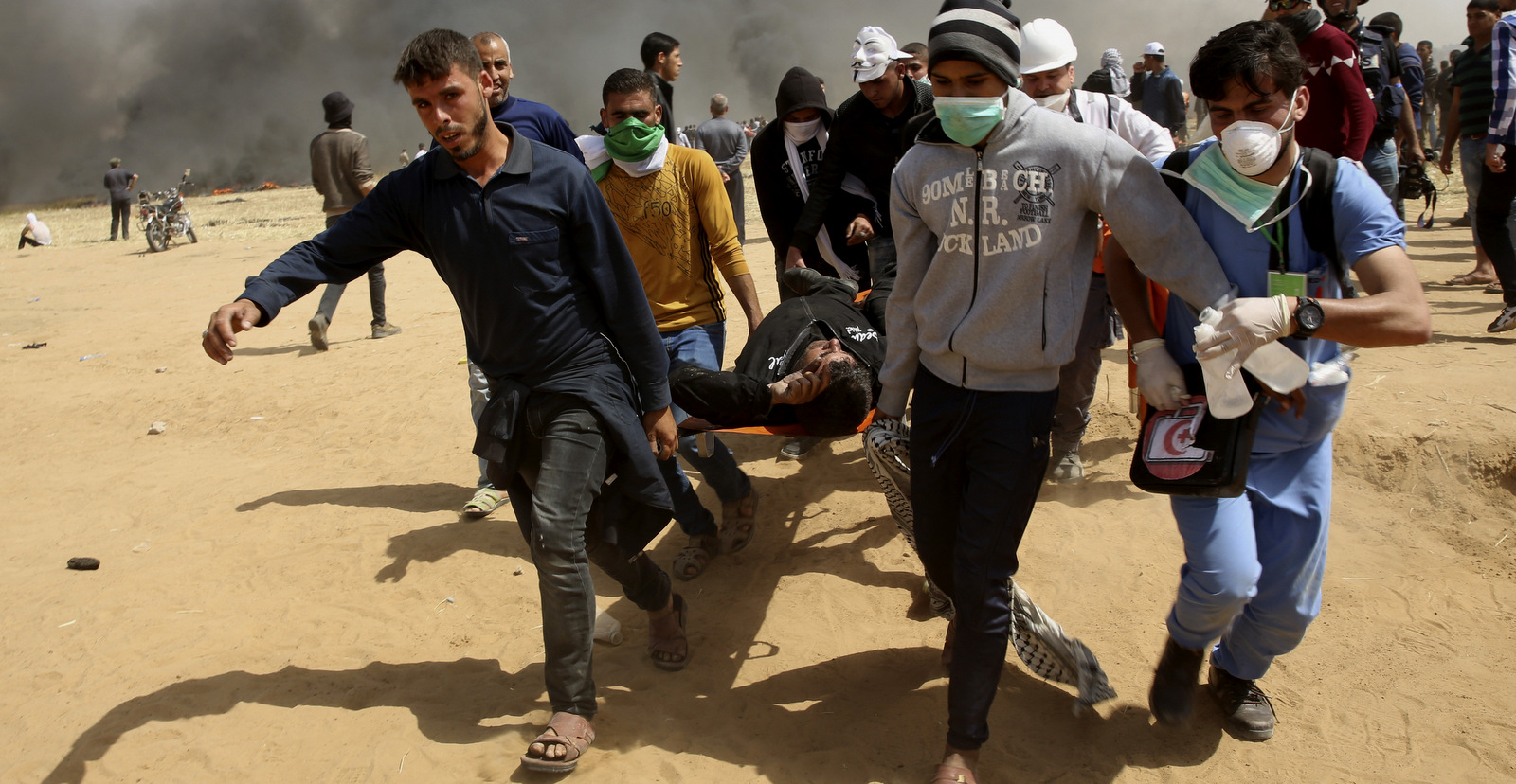 Palestinian protesters evacuate a wounded youth during clashes with Israeli troops along Gaza' class=