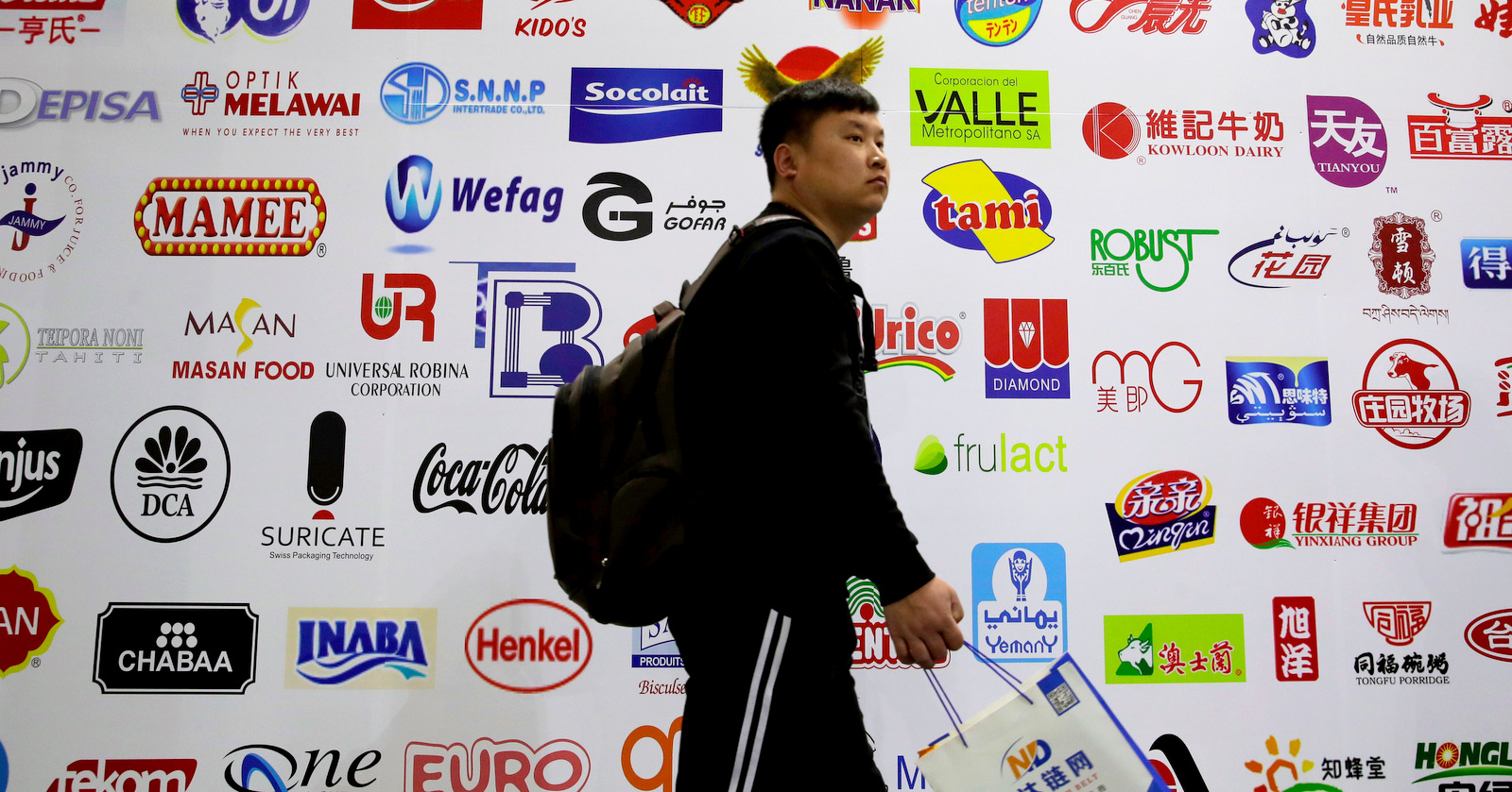In this April 12, 2018, photo, a man walks by a billboard displaying a Chinese company developed packaging machinery for local and foreign food and beverage companies at the International soybean exhibition in Shanghai. (AP/Andy Wong)