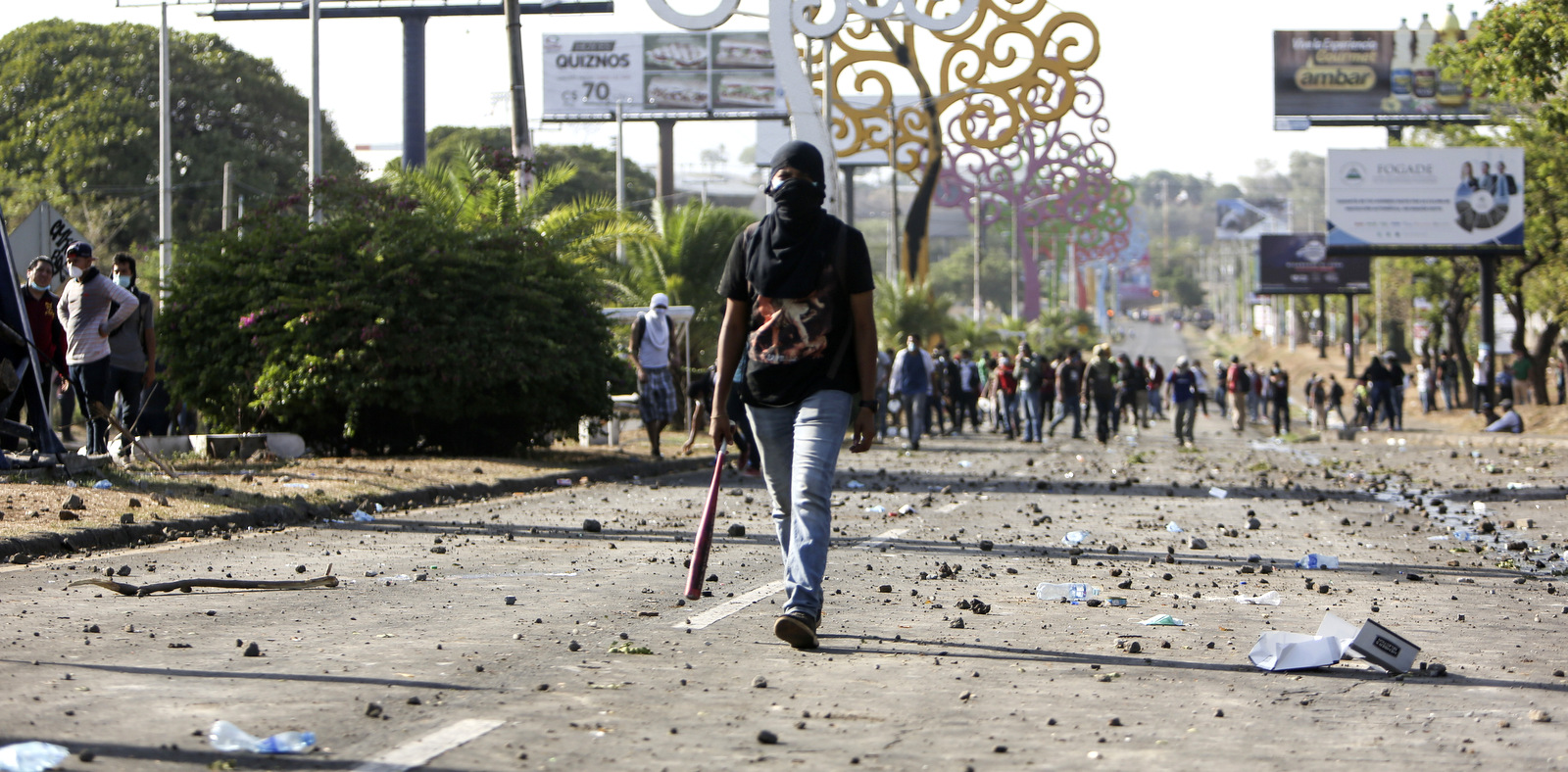 2018年4月20日星期五，在尼加拉瓜马那瓜，一名蒙面示威者在主要街道上散步，散落着碎片。尼加拉瓜连续三天的抗议活动在宣布有争议的社会保障改革之后，周五又造成第五次死亡和数十人受伤。国际组织对此表示关注，并呼吁丹尼尔奥尔特加政府尊重人民的声音。 （AP Photo / Alfredo Zuniga）
